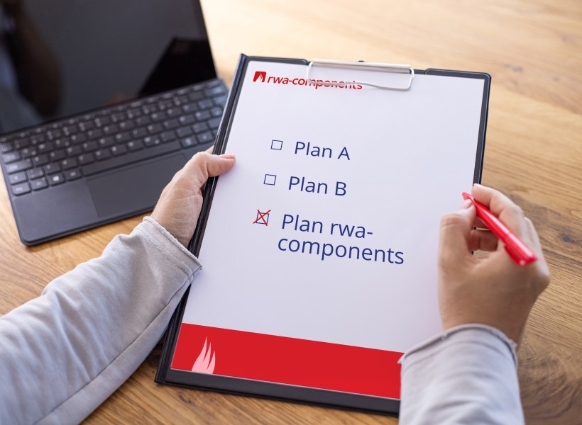 rwa-components Mitarbeiterin hat ein Klemmbrett in der einen und einen Kugelschreiber in der anderen Hand. Auf dem Papier am Klemmbrett gilt es folgendes anzukreuzen: Plan A, Plan B und Plan rwa-components. Es ist Plan rwa-components angekreuzt.